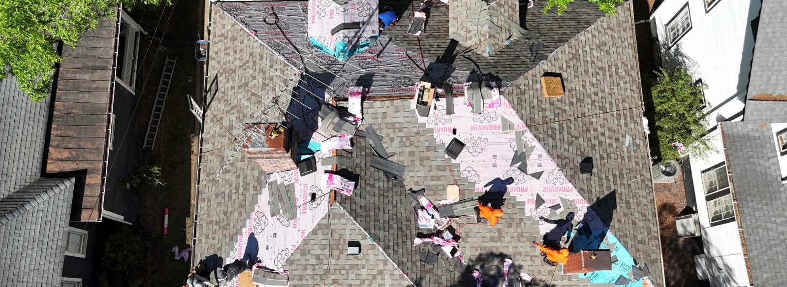 Aerial view of a roof installation in progress in Ballantyne, NC — ProArmor synthetic underlayment with shingle bundles staged on a complex multi-peak roof