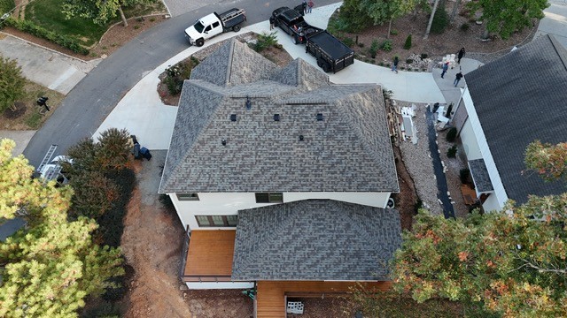 Aerial view of a roof installation in progress on a Huntersville, NC home — Charlotte Ace Roofing crew and dump trailer on driveway