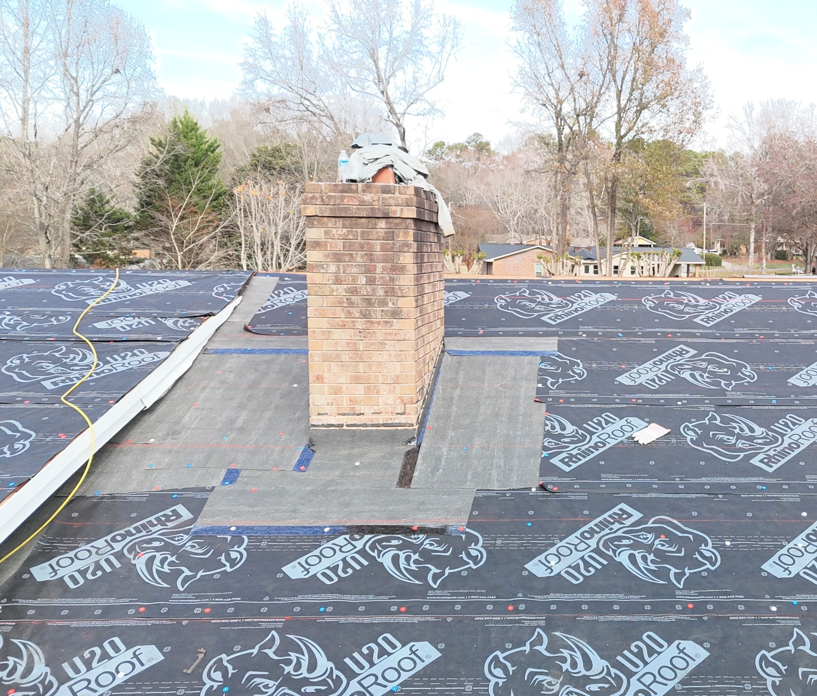 Roof replacement in progress on an Indian Trail, NC home — chimney flashing detail with RhinoRoof U20 underlayment