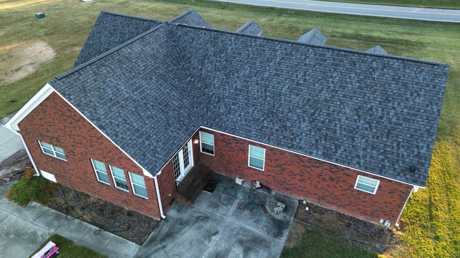Completed dark-gray architectural shingle roof replacement on a brick ranch home in Monroe, NC by Charlotte Ace Roofing