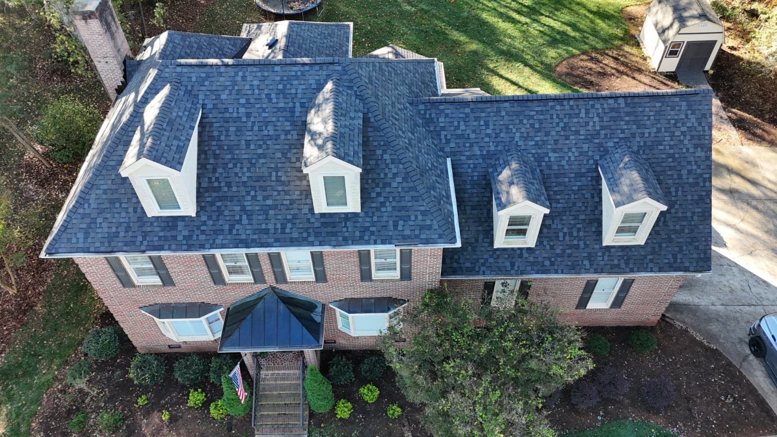 Completed dark architectural shingle roof on a red brick colonial home with multiple dormers in the Waxhaw, NC area — installed by Charlotte Ace Roofing